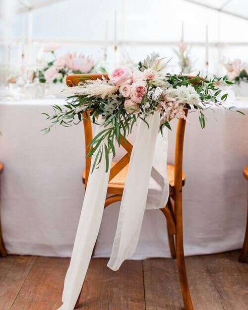 Wedding chair decor with roses and white ribbon