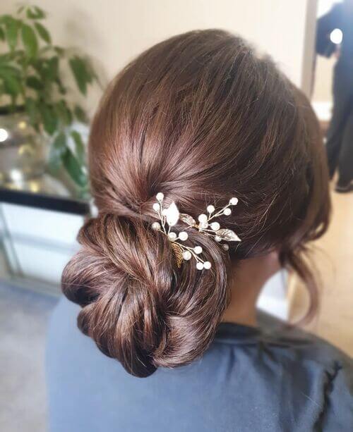Sleeked-back bun with floral clip bridesmaids hairstyle idea